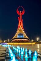 Usbekistan, Taschkent - - kann 5, 2023 beleuchtet Monument von Unabhängigkeit im das bilden von ein Stele mit ein Humo Vogel, Brunnen und winken Flaggen im das Neu Usbekistan Park beim nachts. foto