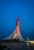 Usbekistan, Taschkent - - kann 5, 2023 beleuchtet Monument von Unabhängigkeit im das bilden von ein Stele mit ein Humo Vogel, Brunnen und winken Flaggen im das Neu Usbekistan Park beim nachts. foto