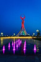 Usbekistan, Taschkent - - kann 25, 2023 beleuchtet Monument von Unabhängigkeit im das bilden von ein Stele mit ein Humo Vogel und Brunnen im das Neu Usbekistan Park beim nachts. foto