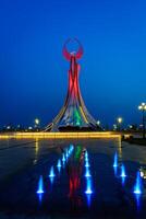 Usbekistan, Taschkent - - kann 25, 2023 beleuchtet Monument von Unabhängigkeit im das bilden von ein Stele mit ein Humo Vogel und Brunnen im das Neu Usbekistan Park beim nachts. foto