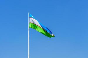 Flagge von Usbekistan winken auf ein tagsüber Himmel Hintergrund. foto
