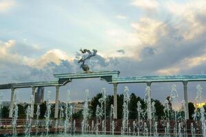 Denkmal und Reihen von Brunnen beleuchtet durch Sonnenlicht beim Sonnenuntergang oder Sonnenaufgang im das Unabhängigkeit Platz beim Sommer, Taschkent. foto