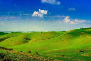 Hügel und Berge bedeckt mit jung Grün Gras und beleuchtet durch das Sonne auf ein sonnig Tag. foto