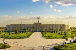 Usbekistan, Taschkent - - Oktober 4, 2023 das Gebiet von das Park Neu Usbekistan mit Monument von Unabhängigkeit im das bilden von ein Stele mit ein Humo Vogel beim Sonnenuntergang. foto