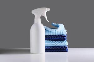 Reinigung Produkt mit ein Sprühgerät auf ein Hintergrund von ein Blau Mikrofaser Tuch. foto