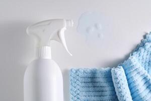 Reinigung Produkt mit ein Sprühgerät auf ein Hintergrund von ein Blau Mikrofaser Tuch. foto