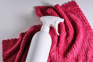 Reinigung Produkt mit ein Sprühgerät auf ein Hintergrund von ein rot Mikrofaser Tuch. foto