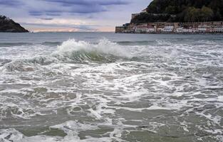 ein Welle geht kaputt im das Bucht von san Sebastian, Spanien, während Sonnenuntergang foto