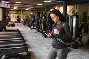 jung Frau Trinken Wasser und nehmen ein brechen nach trainieren im Fitnessstudio foto