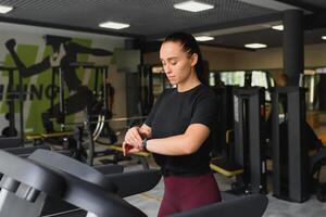 Frau Züge auf ein Laufband im das Fitnessstudio. jung Fitness Mädchen Laufen auf Laufband Maschine. Sport Übungen zum Gewicht Verlust foto