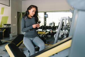 Herrlich jung Frau SMS und Sozial Vernetzung während im ein Fitnessstudio. foto