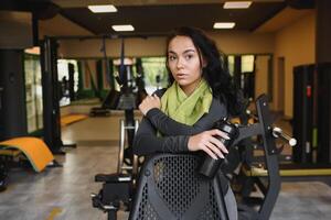 jung Frau Trinken Wasser und nehmen ein brechen nach trainieren im Fitnessstudio foto