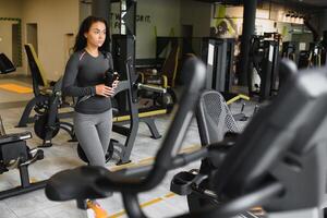 jung Frau Trinken Wasser und nehmen ein brechen nach trainieren im Fitnessstudio foto