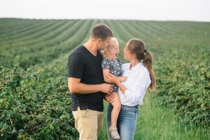 glücklich Familie Gehen im das Park. Mutter, Papa und Tochter gehen draußen, Eltern halten das Baby Mädchen Hände. Kindheit, Elternschaft, Familie Fesseln, Ehe Konzept. foto