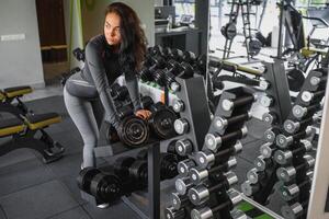 sportlich Frau im Fitnessstudio. Frau Heben Gewichte und Arbeiten auf ihr Truhe beim das Fitnessstudio. foto