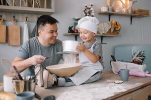 jung Mann und seine Sohn mit Ofen Blatt im Küche. Vater mit wenig Sohn auf das Küche. foto