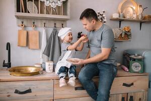 jung Mann und seine Sohn mit Ofen Blatt im Küche. Vater mit wenig Sohn auf das Küche. foto