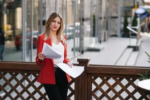 Porträt von Geschäft Frauen im Gefühl von konzentrieren Stress und sehen Stand und halt das Papier Datei Blatt im das draussen Fußgänger gehen Weg mit das Stadt Raum von Außen modern Fassade Gebäude foto