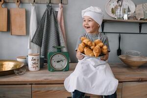 jung Junge süß auf das Küche Koch Koch im Weiß Uniform und Hut in der Nähe von Tisch. hausgemacht Lebkuchen. das Junge gekocht das Schokolade Kekse. foto