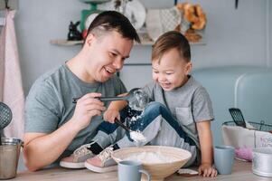 jung Mann und seine Sohn mit Ofen Blatt im Küche. Vater mit wenig Sohn auf das Küche foto