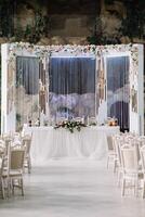 Hochzeit Dekor - - Frühling Blumen und Eukalyptus Geäst, Kerze Büchsen und lila Stoff im das Hochzeit Bogen auf das Hintergrund von Grün Gras und das Fluss. foto