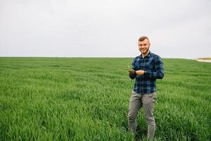 Agronom mit Grün Weizen im Hände. Feld von Weizen auf Hintergrund. foto