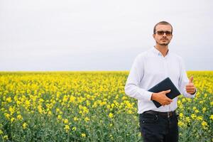 jung Agronom hält Tablette im vergewaltigen Feld. Landwirtschaft Konzept. landwirtschaftlich Ingenieur Stehen im ein vergewaltigen Feld mit ein Tablette im Sommer. foto