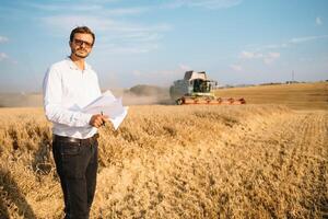 glücklich Farmer im das Feld Überprüfung Mais Pflanzen während ein sonnig Sommer- Tag, Landwirtschaft und Essen Produktion Konzept foto