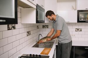 Mann Schneiden frisch Fisch im Küche im heim. Mann schlachten Fisch zum kochen. foto