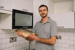 Mann Schneiden frisch Fisch im Küche im heim. Mann schlachten Fisch zum kochen. foto