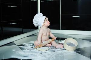 wenig Junge Sitzung auf Teppich im Küche spielen mit Kochen Töpfe. süß Junge Kochen im Küche beim Zuhause foto