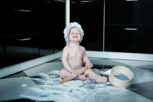 wenig Junge Sitzung auf Teppich im Küche spielen mit Kochen Töpfe. süß Junge Kochen im Küche beim Zuhause foto