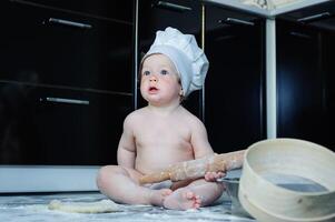 wenig Junge Sitzung auf Teppich im Küche spielen mit Kochen Töpfe. süß Junge Kochen im Küche beim Zuhause foto