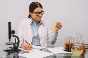 schön medizinisch Ärzte im Handschuhe und Brille sind Arbeiten mit Substanzen im Prüfung Röhren und Mikroskop beim das Labor foto