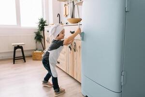 jung Junge süß auf das Küche Koch Koch im Weiß Uniform und Hut in der Nähe von Tisch. Weihnachten hausgemacht Lebkuchen. das Junge gekocht das Schokolade Kekse. foto