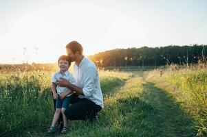 gut aussehend Papa mit seine wenig süß Sohn sind haben Spaß und spielen auf Grün grasig Rasen. glücklich Familie Konzept. Schönheit Natur Szene mit Familie draussen Lebensstil. Familie ruhen zusammen. Väter Tag. foto