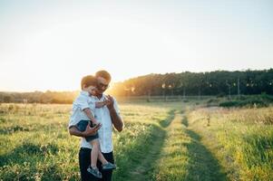 gut aussehend Papa mit seine wenig süß Sohn sind haben Spaß und spielen auf Grün grasig Rasen. glücklich Familie Konzept. Schönheit Natur Szene mit Familie draussen Lebensstil. Familie ruhen zusammen. Väter Tag. foto