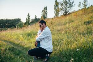 gut aussehend Papa mit seine wenig süß Sohn sind haben Spaß und spielen auf Grün grasig Rasen. glücklich Familie Konzept. Schönheit Natur Szene mit Familie draussen Lebensstil. Familie ruhen zusammen. Väter Tag. foto