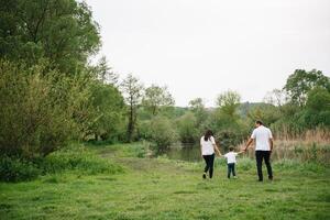 glücklich Familie Mutter Vater und Kind Sohn auf Natur auf Sonnenuntergang. Mutter, Papa und Kind Lachen und umarmen, genießen Natur außen. sonnig Tag, gut Stimmung. Konzept von ein glücklich Familie. foto