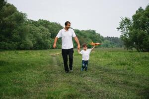 Vater und Sohn spielen im Flieger. Übermensch Papa und Sohn haben Spaß. Phantasie und Träume von Sein ein Pilot. Kind Pilot mit Flugzeug auf Väter zurück. Reise und Ferien im Sommer. Freiheit. foto