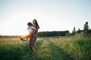 stilvoll Mutter und gut aussehend Sohn haben Spaß auf das Natur. glücklich Familie Konzept. Schönheit Natur Szene mit Familie draussen Lebensstil. glücklich Familie ruhen zusammen. Glück im Familie Leben. Mütter Tag foto