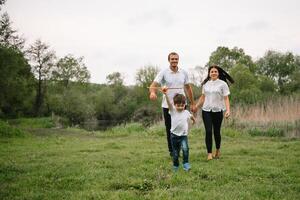 Vater, Mutter und Sohn spielen mit Spielzeug Flugzeug im das Park. freundlich Familie. Menschen haben Spaß draußen. Bild gemacht auf das Hintergrund von das Park und Blau Himmel. Konzept von ein glücklich Familie foto