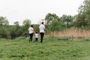 glücklich Familie Mutter Vater und Kind Sohn auf Natur auf Sonnenuntergang. Mutter, Papa und Kind Lachen und umarmen, genießen Natur außen. sonnig Tag, gut Stimmung. Konzept von ein glücklich Familie. foto