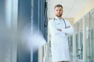 Porträt von gut aussehend jung Arzt auf Krankenhaus Gang foto