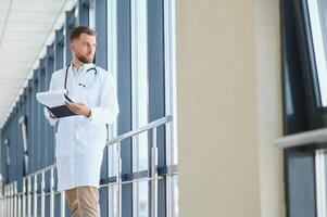 Porträt von ein männlich Arzt Stehen im ein Krankenhaus Gang. foto