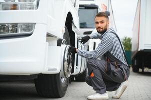 Arbeiten mit beschädigt Reifen. jung LKW Treiber ist mit seine Fahrzeug beim tagsüber foto