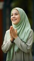 ai generiert Porträt von ein ziemlich Muslim Frau tragen Grün Schal beten und lächelnd draussen. religiös, Frieden und Glück Konzept foto