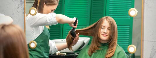 Friseur Herstellung Haar Styling zum das Frau während Kämmen mit Haarbürste, Kamm im ein Haar Salon. foto