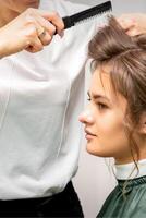 Fachmann Friseur tun Frisur zum ein schön Brünette jung Frau mit lange Haar. Konzept von Mode und Schönheit. foto