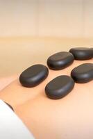 heiß Stein Massage Therapie. kaukasisch jung Mann bekommen ein heiß Stein Massage auf zurück beim Spa Salon. foto